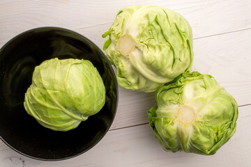 Fototapeta premium Three juicy organic cabbage on a painted wooden table, top view.
