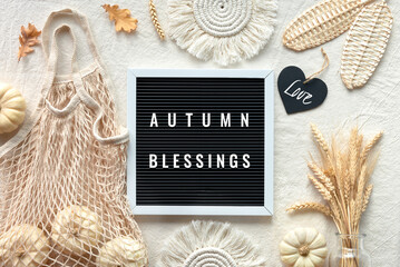 Off white textile background, natural Fall decorations. Text Autumn Blessings on letter board. Flat...