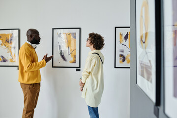 Multiethnic couple discussing modern art together during exhibition at gallery