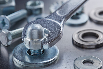 Wrench tightens steel cap nut in steel billet. Spanner, bolt, screw and nuts.