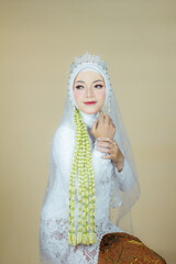 beautiful model, wearing hijab, Javanese Indonesian wedding dress in an indoor photography studio, with Javanese wedding dress attributes