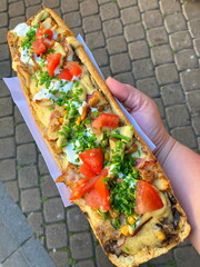 Delicious long polish Zapiekanka  baguette outdoor. Traditional Polish fast food, Krakow street food. Hot sandwich with cheese, sausage, tomatoes. Polish pizza. 