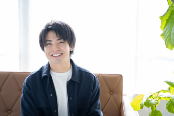 リビングのソファーに座りリラックスする20代男性