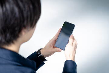 スマホを見つめる20代男性-リビングのソファーに座りリラックス