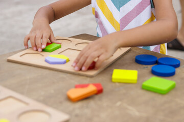 Little girl making colorful wooden puzzle