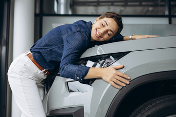 Woman hugging a new car in a car showroom