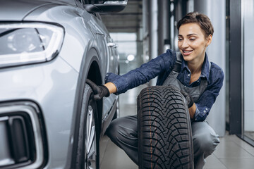 Woman car mechanic changing tires at car service © Petro