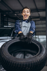 Obraz na płótnie Canvas Woman car mechanic changing tires at car service