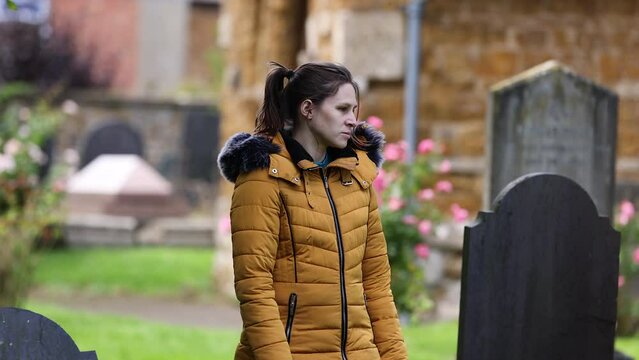 Young girl walking slowly through church cemetery graveyard