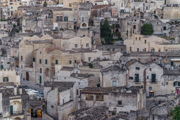 Fototapeta na wymiar old stone houses and churches on the ravine slopes in the historic center of the old town of Matera. Narrow cobbled streets and cascading buildings with rocks and tightly built-up streets