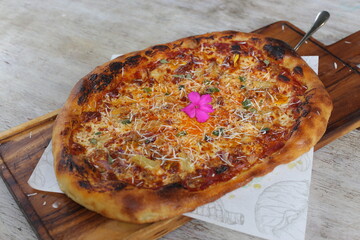 Hawaiian crispy stone fried pizza served in a cutting board isolated on grey background side view