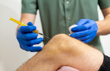 Doctor hand holding syringe for injection to knee. Knee medical injection.