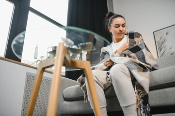 Sick Woman.Flu.Woman Caught Cold. Sneezing into Tissue. Headache. Virus .Medicines. Sick woman with a headache sitting on a sofa.