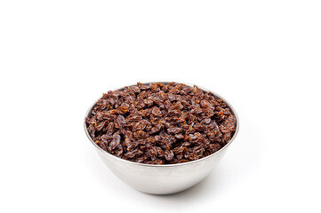 Dark-colored raisins lying in a metal container, shot on a white background.