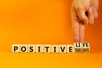 Positive thoughts and life symbol. Concept words Positive thoughts or Positive life on wooden cubes. Businessman hand. Beautiful orange background. Business positive thoughts life concept. Copy space