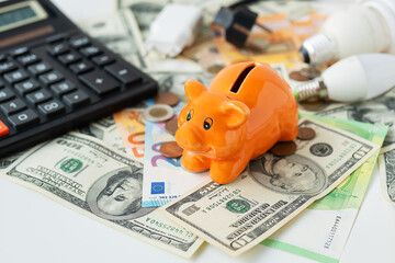 Piggy piggy bank of orange color soit on curry. Calculator, euro and dollar banknotes, coins. Tax time, bill payment, calculator for counting.