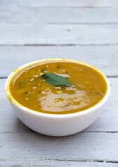 Closeup of Ghugni or Yellow Pea Curry in a White Bowl Isolated on White Wooden Background in Vertical Orientation