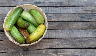 Top View of Cucumber in a Bamboo Basket Isolated on Wooden Background with Copy Space