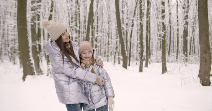 Mother and daughter having fun in winter forest