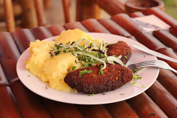 Cutlets and mashed potatoes with greens on a plate on a slice of twigs