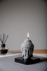 Statuette with candlestick. Statue of Buddha, incense sticks and burning candle. Aromatherapy, home fragrance. Concept of home relaxation and anti stress, zen buddhism.
