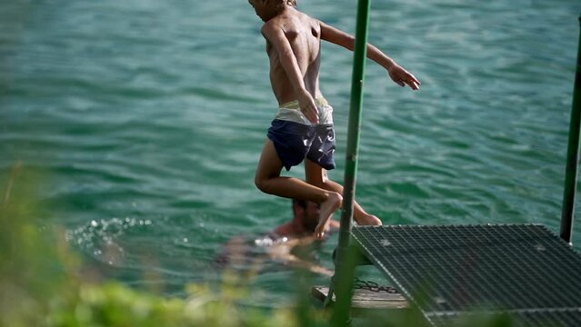 One boy jumping into water in super slow motion 240 fps. Child enjoying hot summer day diving into fresh lake