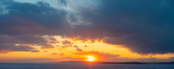 Naklejka na ściany i meble Sunset on the seashore and sky with thick clouds