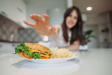 A woman's hand reaches for a big juicy burger.