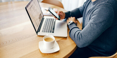 Close up of cup of fresh coffee on the table with entrepreneur in the background working.