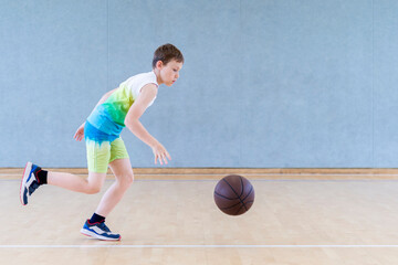 Fototapeta na wymiar School kid playing basketball in a physical education lesson. Horizontal education poster, greeting cards, headers, website