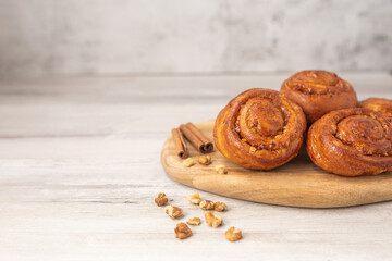 Sweet rolls with cinnamon on wooden board. Caramel buns with nuts.