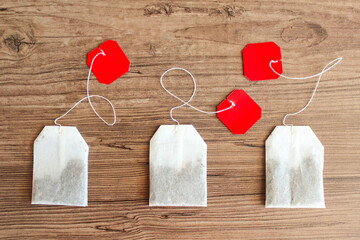 Three tea bags with red label on wooden background