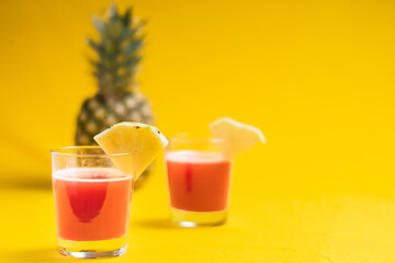 Pineapple juice in glass closeup near sliced fruit with spash and dripping liqid for summer vibes.