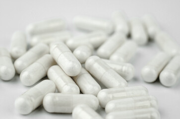 White medical capsules on a white background, selective focus