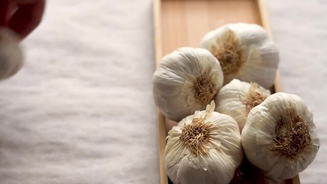 Close-up, male hands place garlic heads on wooden bowl