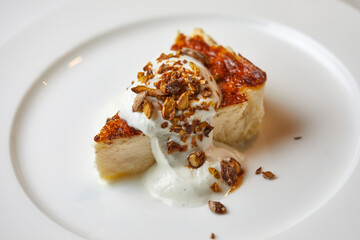 cheesecake with nuts and ice cream on a white plate