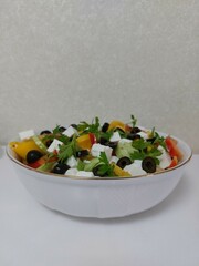 Delicious Greek salad. Vegetable mix. Tomatoes, cucumbers, onions, cabbage, olives, cheese and greens