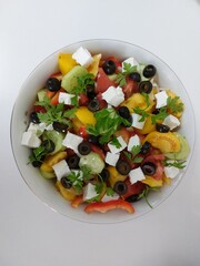 Delicious Greek salad. Vegetable mix. Tomatoes, cucumbers, onions, cabbage, olives, cheese and greens
