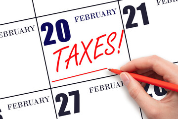 Hand drawing red line and writing the text Taxes on calendar date February 20. Remind date of tax payment
