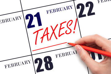 Hand drawing red line and writing the text Taxes on calendar date February 21. Remind date of tax payment
