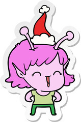 hand drawn sticker cartoon of a alien girl laughing wearing santa hat