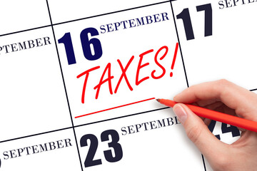 Hand drawing red line and writing the text Taxes on calendar date September 16. Remind date of tax payment