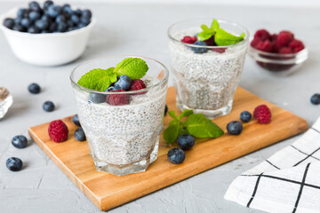 Healthy breakfast or morning with chia seeds vanilla pudding raspberry and blueberry berries on table background, vegetarian food, diet and health concept. Chia pudding with raspberry and blueberry