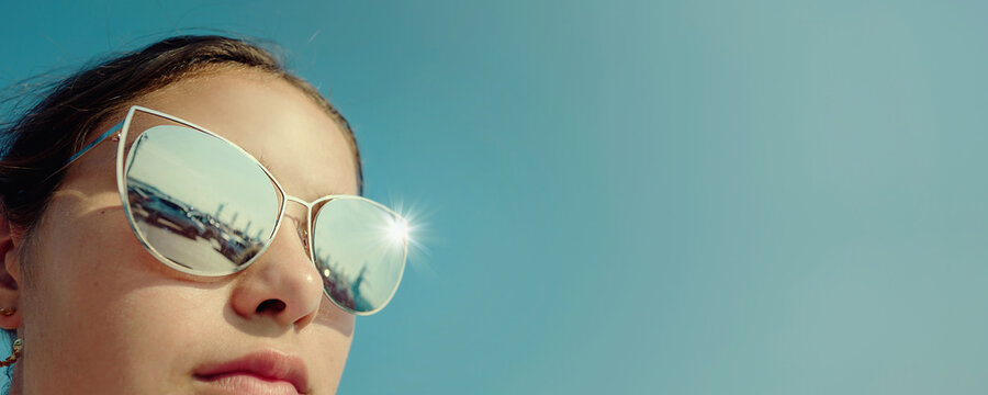 Headshot photography of attractive young woman wearing big sunglasses on blue sky background close up view