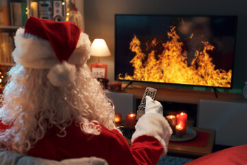 Santa Claus watching a virtual fireplace on TV