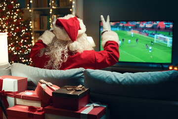 Cheerful Santa Claus watching football on TV