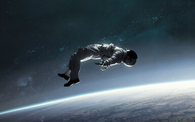 3D illustration of astronaut falling to earth planet. 5K realistic science fiction art. Elements of image provided by Nasa © Vadimsadovski