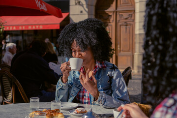 young haitian woman drinking coffee with her eyes closed in an outdoor cafe in autumn - obrazy, fototapety, plakaty