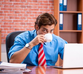 The young employee with excessive work sitting at the office