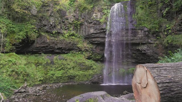 A tall waterfall in a green, forest surrounded by foliage